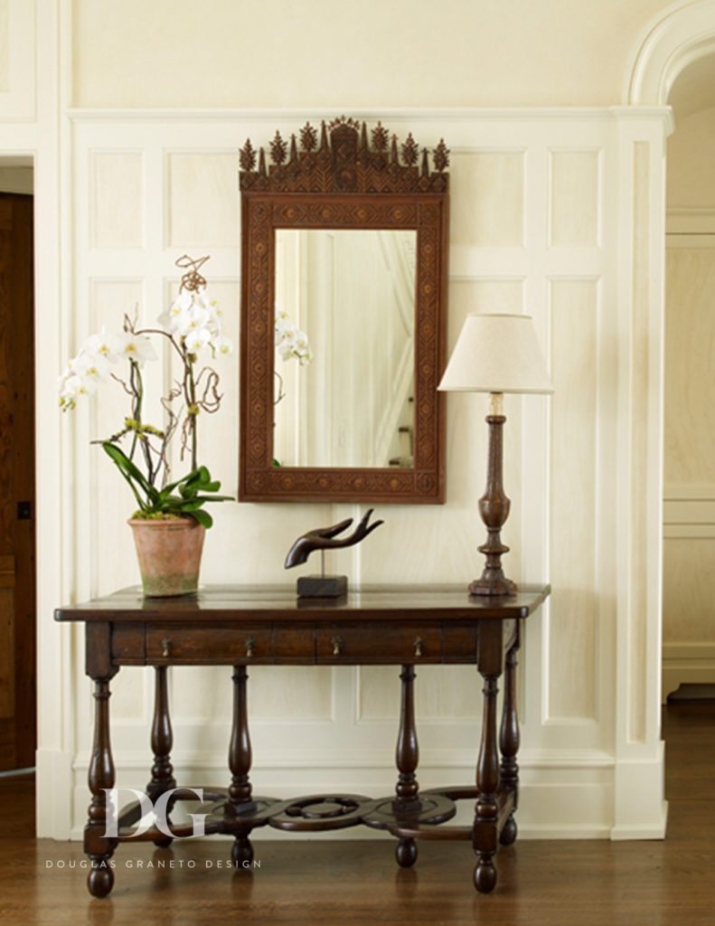 Interior space with a Tramp art style featuring lamp, mirror, and flower vase.