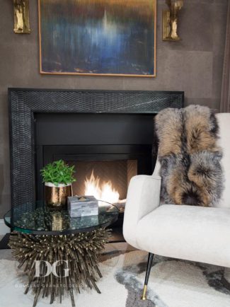 Fire place with white chair that has a fur blanket draped over it