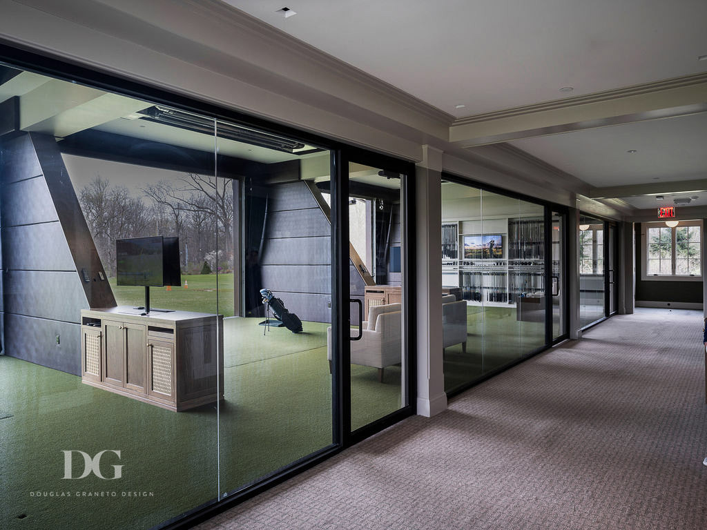 Looking along a row of country club pro shop hitting bays with glass walls