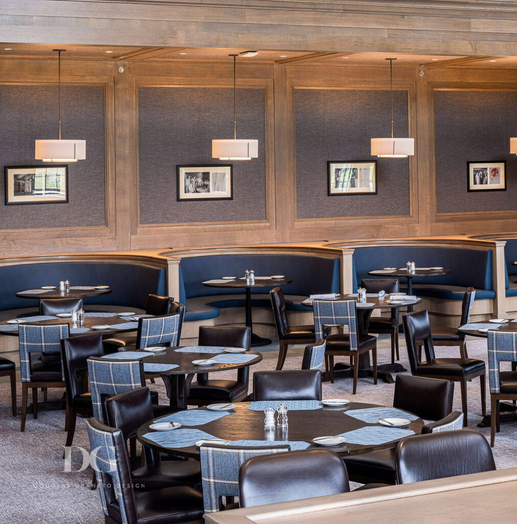 Oak panelled pub dining room with leather and tweed chairs, and a row of curved blue banquettes along the back wall