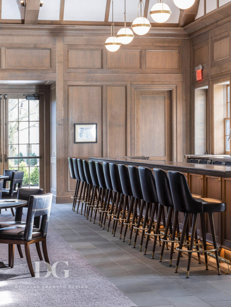 Row of custom leather bar stools at a bar with wood panelling and Hubbardton Forge pendant lights