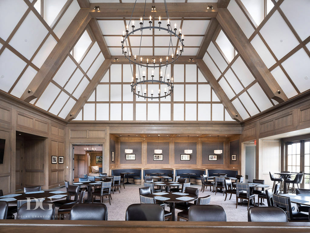 Looking out at a wood panelled pub dining room with leather and blue decor, vaulted ceiling and candle chandeliers