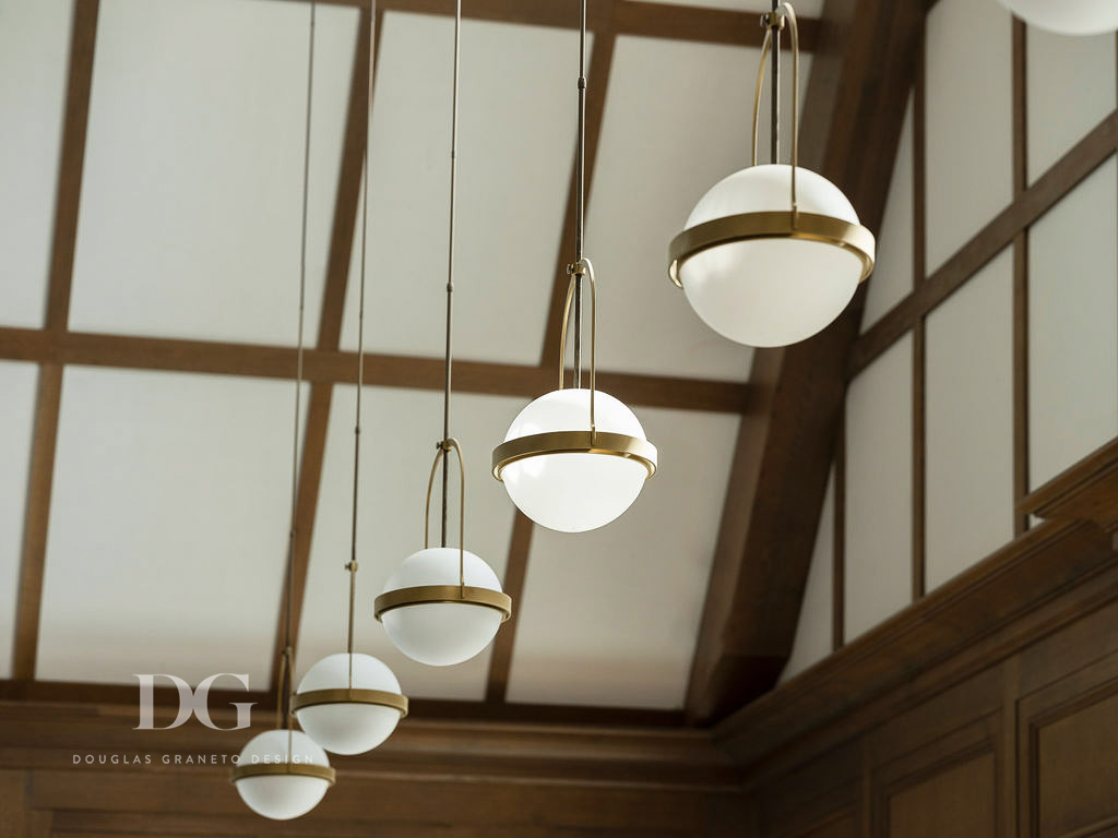 Row of Hubbardton Forge round pendants hanging from wood framed vaulted ceiling