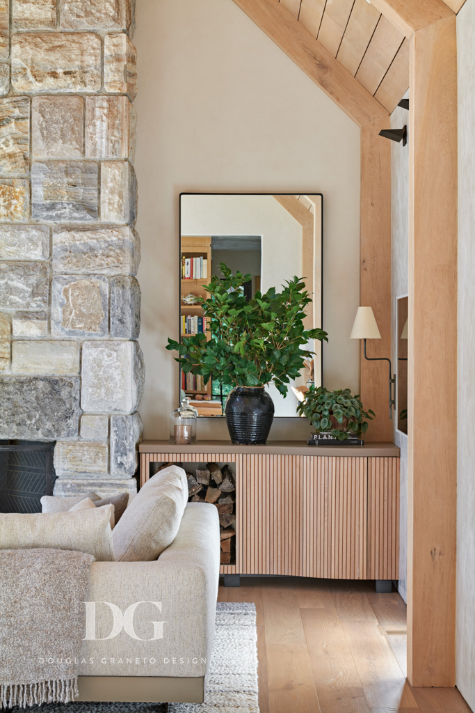 View of corner of Minotti DDC sectional with a Rosemary Hallgarten throw, a stone clad fireplace and custom built-in log storage.