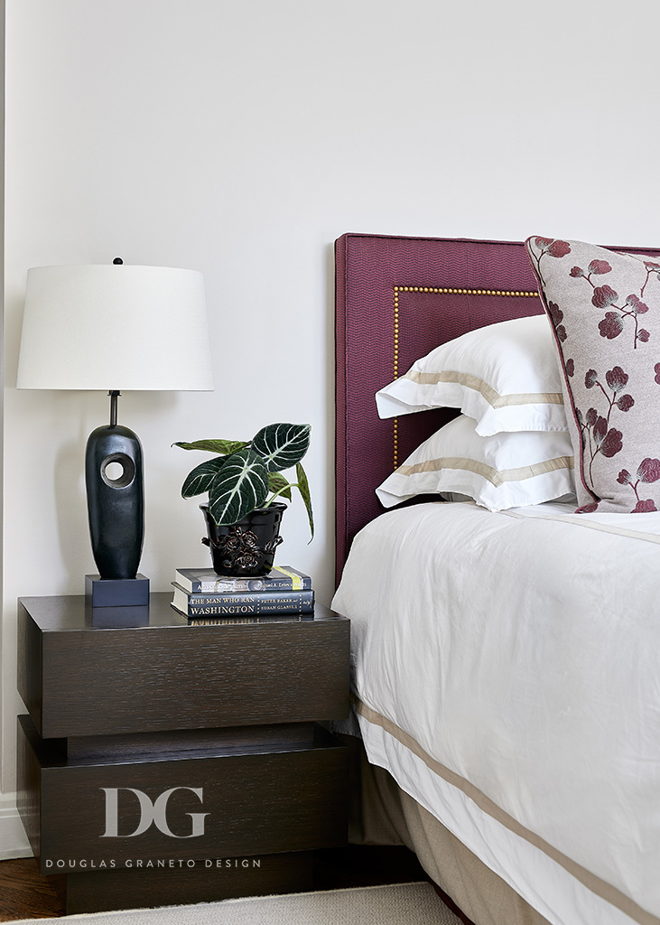 Modern nightstand next to bed with orchid colored upholstered headboard
